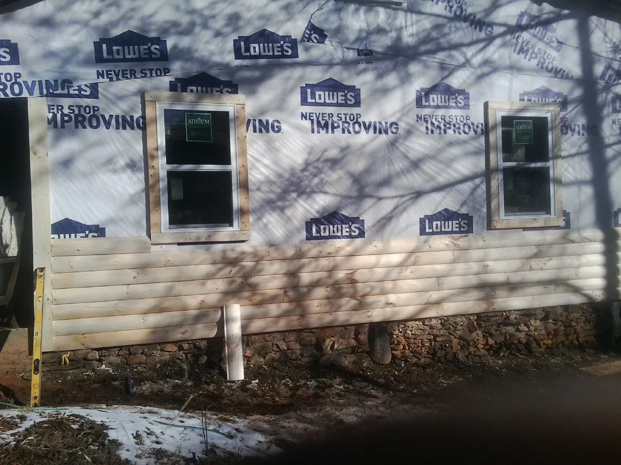 House wrap and new log siding going up on an exterior wall in Hohenwald