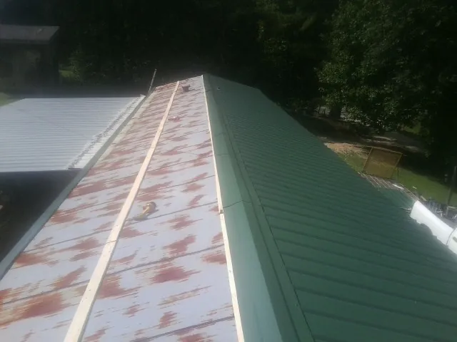 Old rusted panels beside newly installed green metal roofing — Wind Damage Roof Repair by Roofing Brothers in Hohenwald