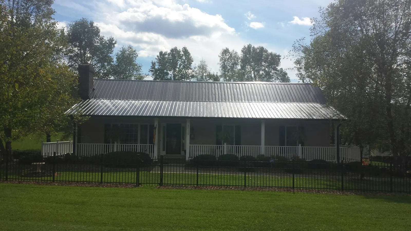 Gray metal roof on a brick ranch with a full width front porch — Gutter Guard Installation work by our crew in Hohenwald