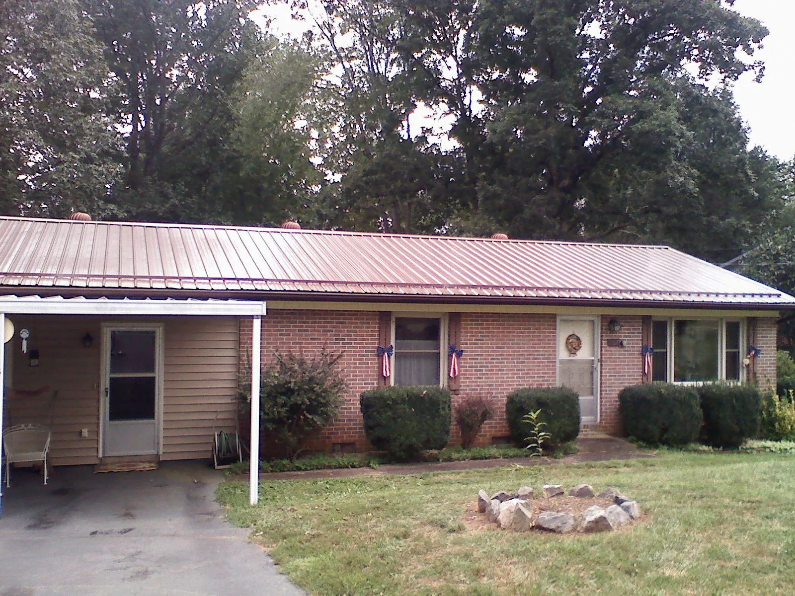 Bronze metal roof and carport on a brick ranch home — Roof Repair work by our crew in Hohenwald