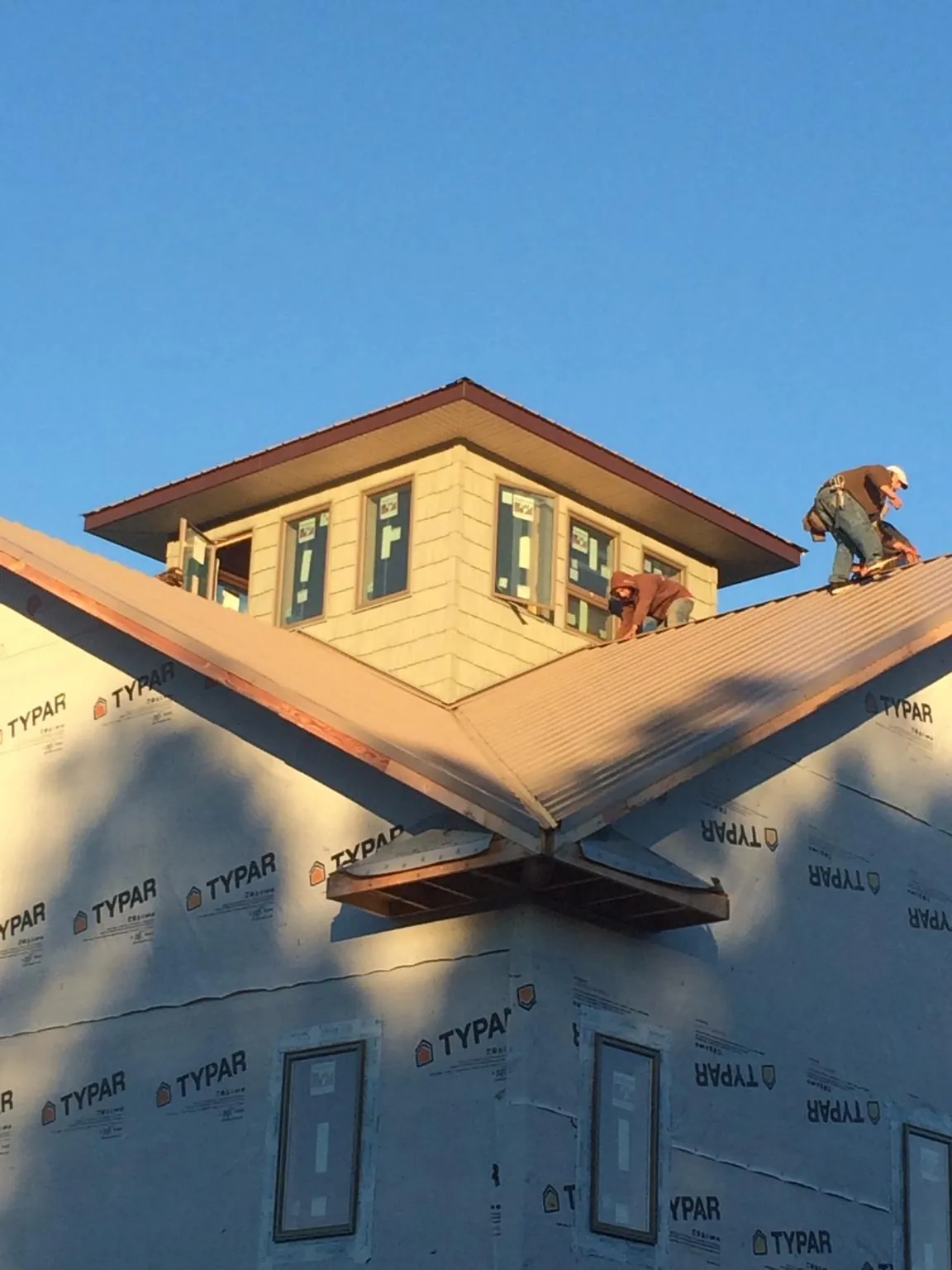 Roofers working around a rooftop cupola on a new metal roof at sunset — Roof Waterproofing in Hohenwald by Roofing Brothers